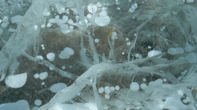 CLOSE UP: Detailed shot of the slippery surface of frozen Lake Abraham full of big methane bubbles. Air bubbles are trapped under a thick layer of ice covering a famous lake in the Canadian Rockies.