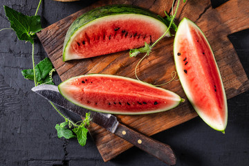 Watermelon slices cut in half on a wooden cutting board.