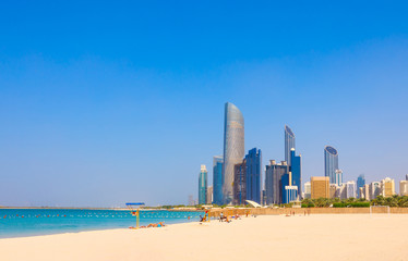 Skyline view of Abu Dhabi panorama with sea, beach and skyscrapers. Sunny summer day in Abu Dhabi - famous tourist destination in UAE. Ideal place for luxury travel and rest - obrazy, fototapety, plakaty