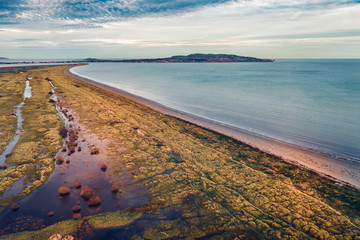 Aerial view over Bull Island shoreline revealing marram grass anchored dunes and view Howth on the...