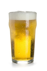 Pint of light cold beer in a glass with a thick cap of foam, bubbles and drops of condensate, isolated on a white background.