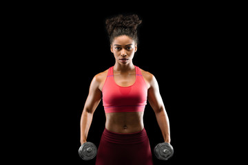Determined young black woman exercising with dumbbells
