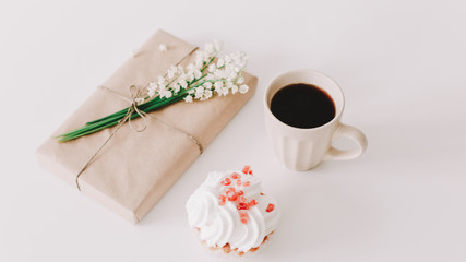 Romantic composition of cup of coffee, gift and flowers on white background. Concept of holiday, birthday, International WomensDay