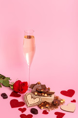 Valentine's day background with red hearts, chocolate candies and glasses of champagne on a pink background. rose and red hearts. Romantic atmosphere.