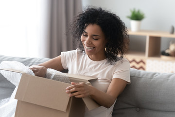 African woman unpacking cardboard box parcel feels happy
