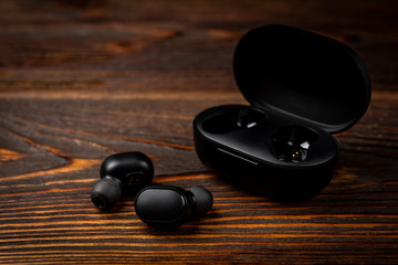 Black wireless headphones on dark wooden background.