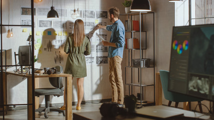 Young Creative Male and Female are Organizing a Mood Board on a Wall of Their Cool Office Loft....