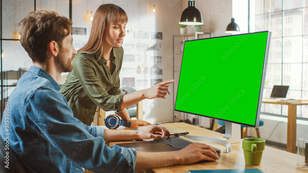Poster female art director consults designer colleague, they work on a personal computer with green screen 