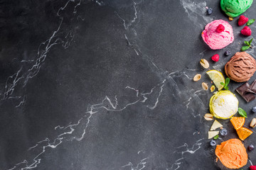 Colorful pastel ice cream with waffle cones and various flavor ingredients, black marble background, copy space top view