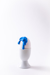 Easter egg with liquid paint on it. Minimalism concept. Classic blue colour trend on white background