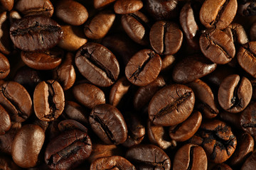 Extreme close up, top down of freshly roasted, shiny coffee beans. Macro food texture background