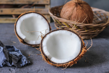 Fototapeta na wymiar Photo of fresh coconut on a table. Tropical palm fruits. Coconut cut in half. Beach fruit. Retro dark background. Rustic wooden board. Front view. Image