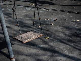 Old lonely wooden swing on sunset time with light and shadow.