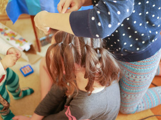 A mother is combing her baby. Mother caring for a child combing hair at home in the bedroom....