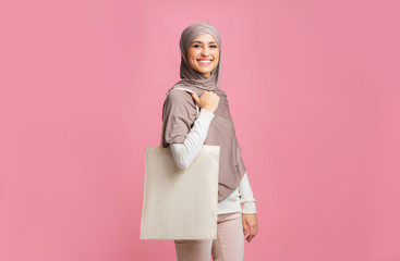 Cheerful islamic woman in headscarf posing with tote eco shopping bag