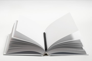 Mockup of closed blank square book and black pencil at white textured paper background