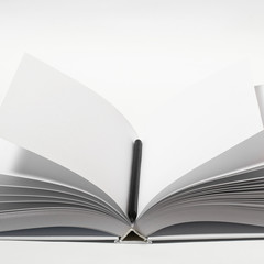 Mockup of closed blank square book and black pencil at white textured paper background