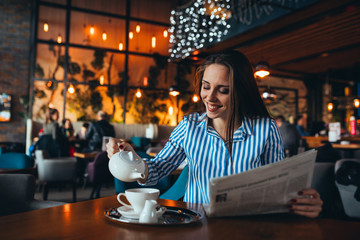woman in cafe drinking tea and reading newspapers