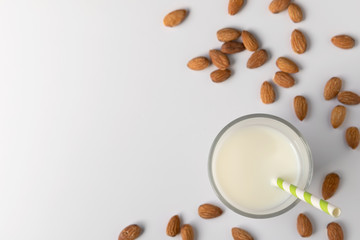 Glasses with almond milk and nuts around it on white background, copy space