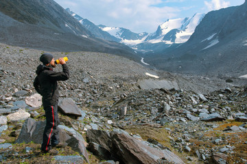 Hiker drinks water from the bottle in alpine landscape. 