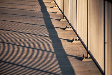 Fototapeta na wymiar The abstract pattern of the shadows of the bridge railing on the pavement on the bridge of the Flussstrasse over the Wöhrder See in Nuremberg, Germany, in the evening light in April 2019