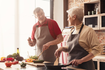 Senior husband and wife cooking dinner at kitchen together