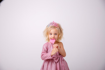 Obraz na płótnie Canvas beautiful little blonde girl with a heart shaped Lollipop