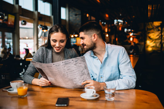 man and woman ordering food in restaurant. looking at the menu