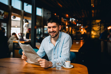 man reading newspapers and drinking coffee in cafeteria