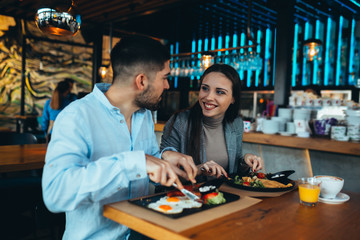 happy couple having breakfast in restaurant or food corner