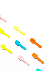 Colored Small plastic ice cream spoon are lined up on a white background, top view