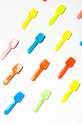 Colored Small plastic ice cream spoon are lined up on a white background, top view