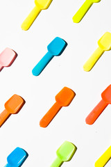 Colored Small plastic ice cream spoon are lined up on a white background, top view