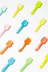 Colored Small plastic ice cream spoon are lined up on a white background, top view