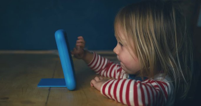 Little toddler using tablet at the dining table