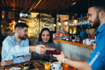 man paying bill using mobile phone in restaurant