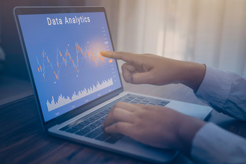 Businessman using a laptop computer with data analytics and statistics information business technology on table top. mockup with clipping path.