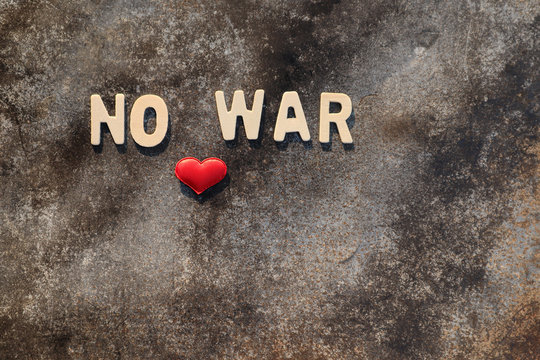 Wooden letters "NO WAR" and red heart shape On the cement background