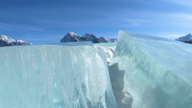 CLOSE UP: Scenic view of glacier behind frozen Lake Abraham on a sunny winter day. Crystallized snow gathers in the large cracks in the ice covering a famous lake in the picturesque Canadian Rockies.