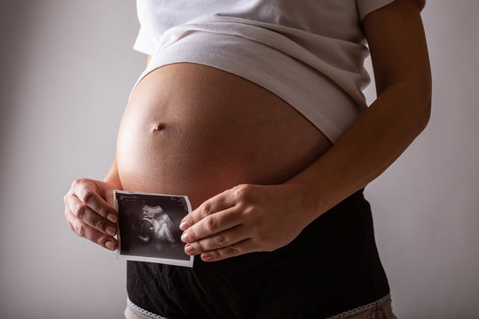 Pregnant woman looks at ultrasound photo in a studio