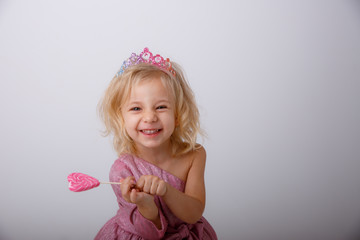 Obraz na płótnie Canvas beautiful little blonde girl with a heart shaped Lollipop