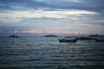 fishing and tourist boats near the shore at sunset on a tropical island