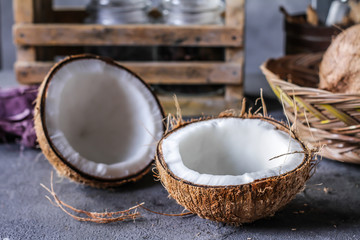 Photo of fresh coconut on a table. Tropical palm fruits. Coconut cut in half. Beach fruit. Retro dark background. Rustic wooden board. Front view. Image