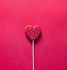 Heart shape red lollipop on the red background. Valentine's day greeting card