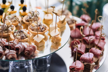 canapes with bacon, cheese, sausage, pears and other snacks on the festive table