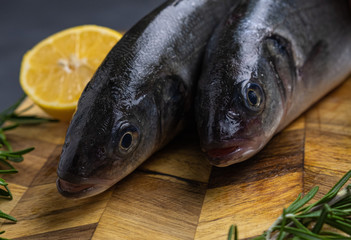 fresh fish with rosemary and lemon on a wooden board