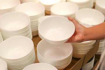 The hand holding the white bowl to select the best to buy and take back home.