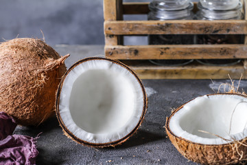 Photo of fresh coconut on a table. Tropical palm fruits. Coconut cut in half. Beach fruit. Retro dark background. Rustic wooden board. Front view. Image