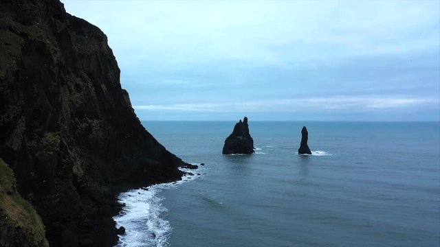 4K Drone Shot Rising Down To The Black Sand Beach In Iceland, Violent Waves Over-Cast. Famous Black Sand Beach In Iceland South Of Iceland, Cloudy Day. Next To Big Rock Cliffs