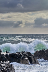 Fototapeta na wymiar Strong waves in the sea hitting the rocks of the coast